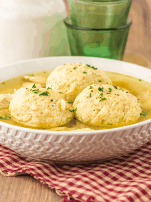 Bowl of traditional Slow Cooker Matzo Ball Soup with fluffy matzo balls, shredded chicken, and fresh dill.