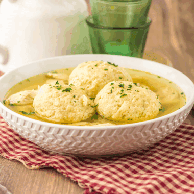 Bowl of traditional Slow Cooker Matzo Ball Soup with fluffy matzo balls, shredded chicken, and fresh dill.