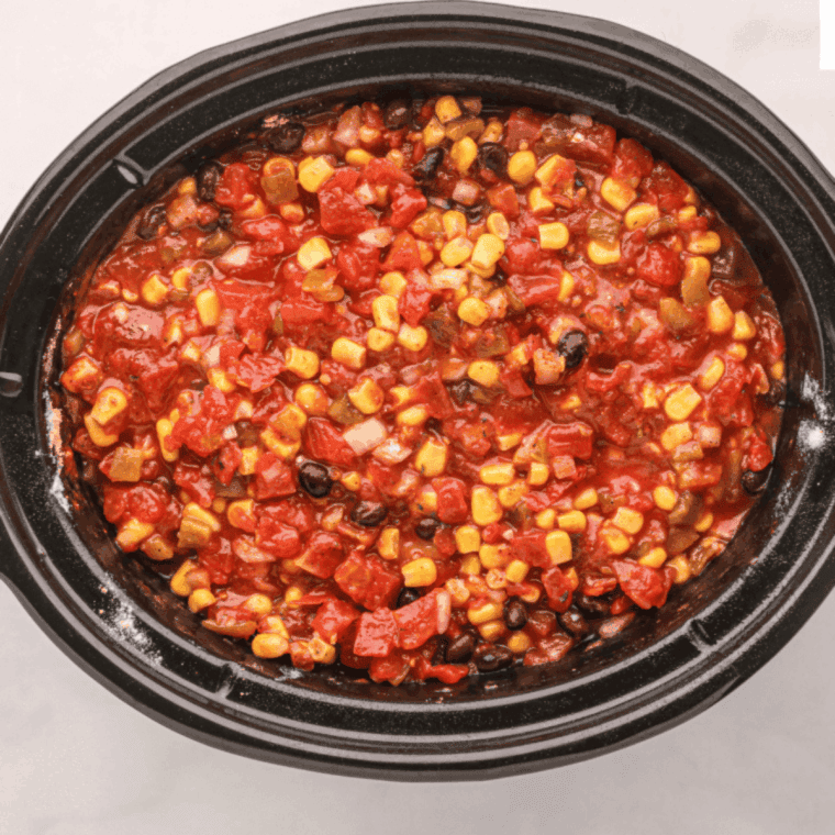 Pork roast coated with a savory spice rub, placed in a slow cooker with chopped onions, beans, diced tomatoes, and topped with liquid smoke and chicken broth.