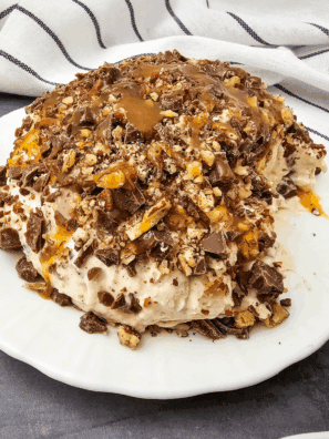 Easy Snickers Cheese Ball rolled in chopped peanuts, served on a platter with vanilla wafers and pretzels.