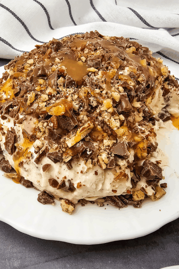 Easy Snickers Cheese Ball rolled in chopped peanuts, served on a platter with vanilla wafers and pretzels for dipping.