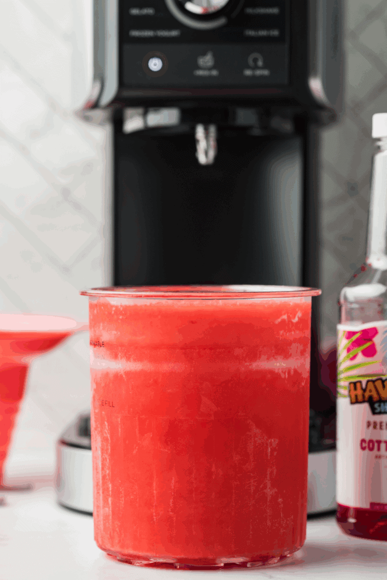 Pouring the cotton candy mixture into a Ninja Creami pint container and securing the lid for freezing.