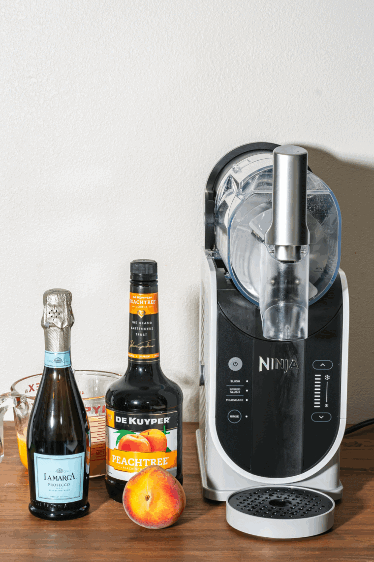 Pouring blended peach mixture into the Ninja Slushi container with prosecco added.