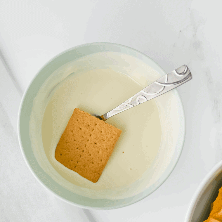 Dipping the graham crackers into the melted chocolate.