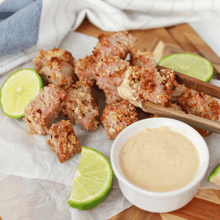 Sliced seared Ahi Tuna steak, showing the pink center and black sesame crust, served with a soy-based dipping sauce and pickled ginger, similar to the Ruth's Chris appetizer.