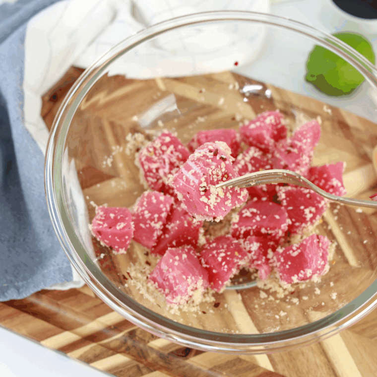 Ahi tuna filet being coated in blackening seasoning in shallow dish