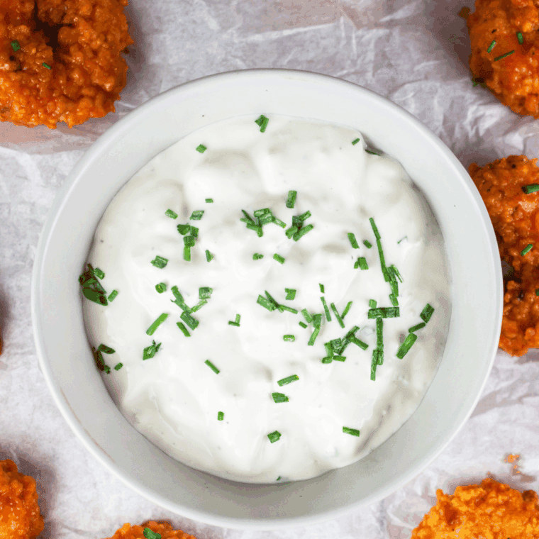 Creamy blue cheese sauce and fresh herbs in glass bowl