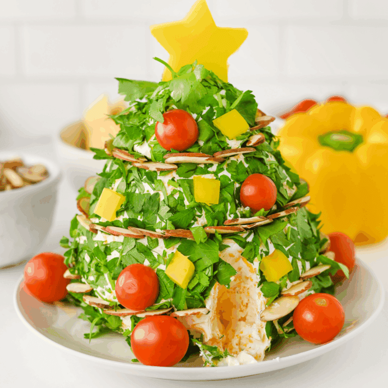 Christmas tree shaped cheese ball served with crackers on board