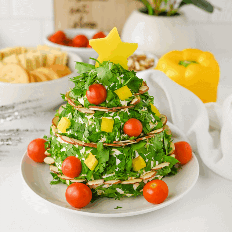 Christmas tree shaped cheese ball decorated with herbs and served with crackers