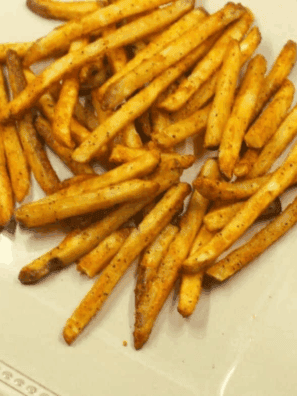 air fryer fries tossed with dill pickle Grinch salt seasoning in a shaker bag