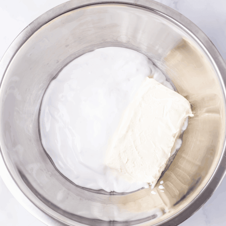 Mixing cream cheese, marshmallow fluff, and peppermint extract with crushed peppermints in a large bowl.
