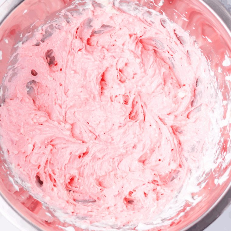 Adding red food coloring to peppermint fluff and mixing until evenly pink.
