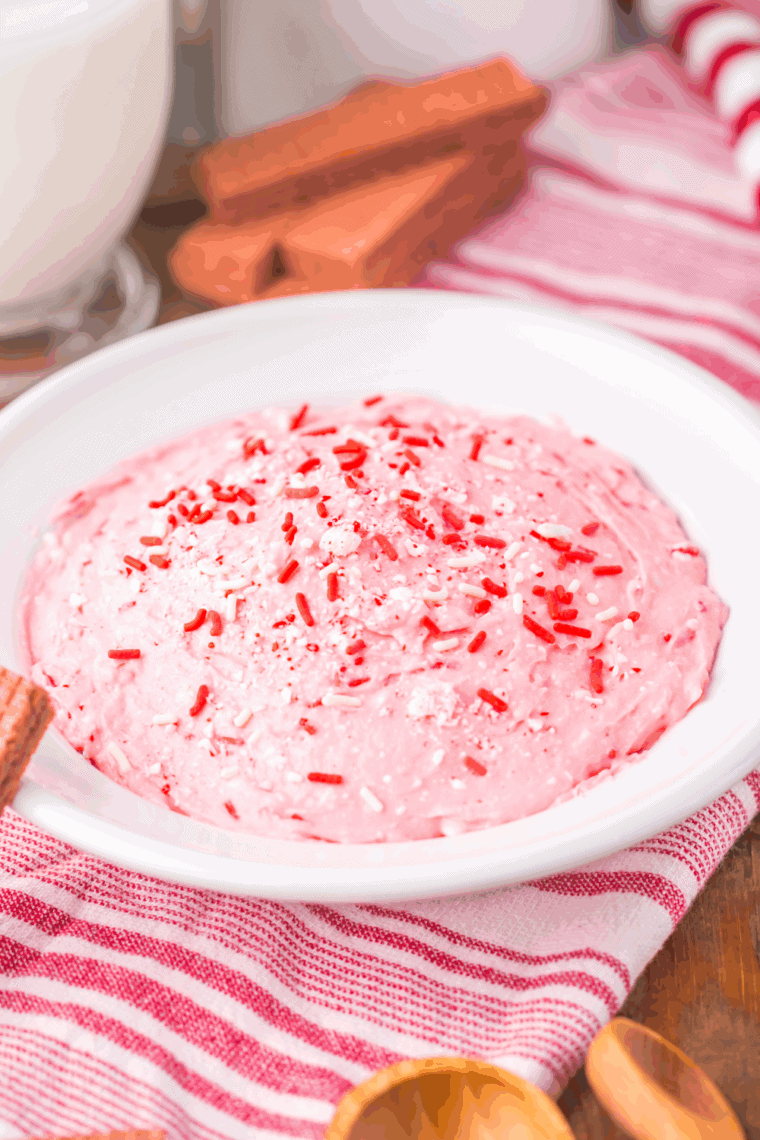 Bowl of creamy Peppermint Fluff topped with crushed candy canes and sprinkles.