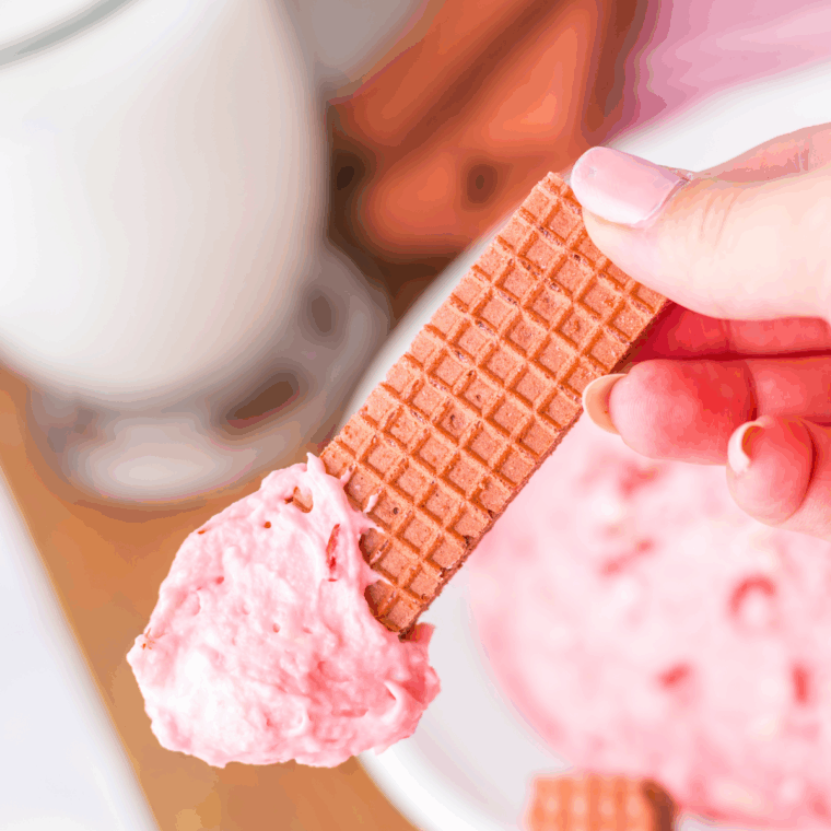 Bowl of Easy Peppermint Fluff topped with crushed candy canes and sprinkles.