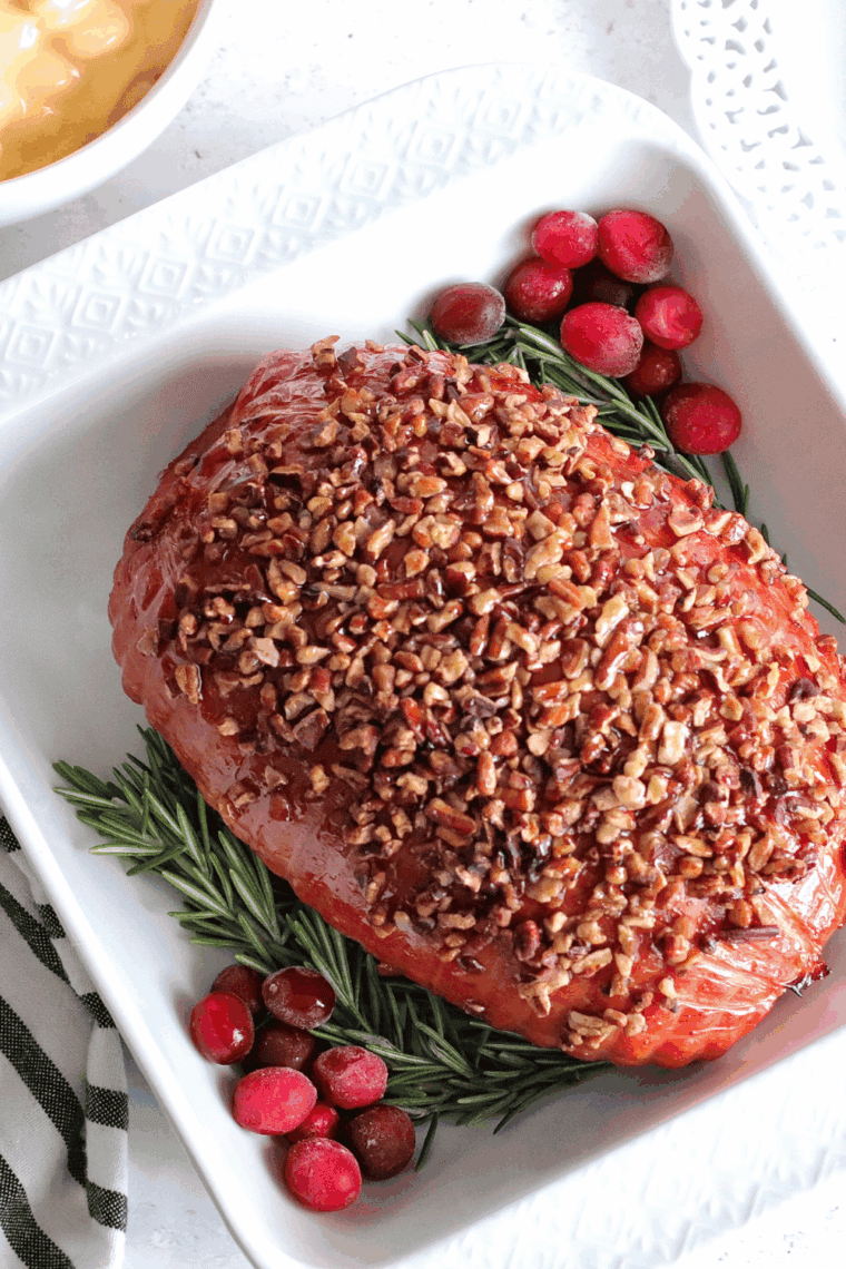 Golden-brown air fryer Christmas ham sliced and garnished with fresh herbs.
