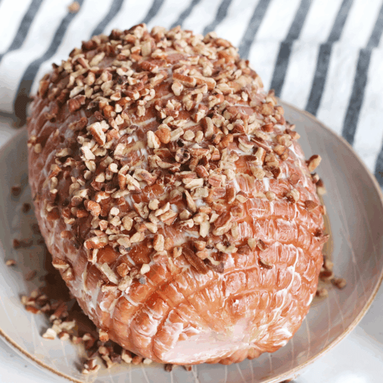 Spreading butter, pouring maple syrup, and pressing pecans onto ham.