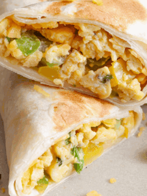 Homemade SuperSonic-style breakfast burrito filled with eggs, sausage, cheese, and tater tots, cut in half on a plate.