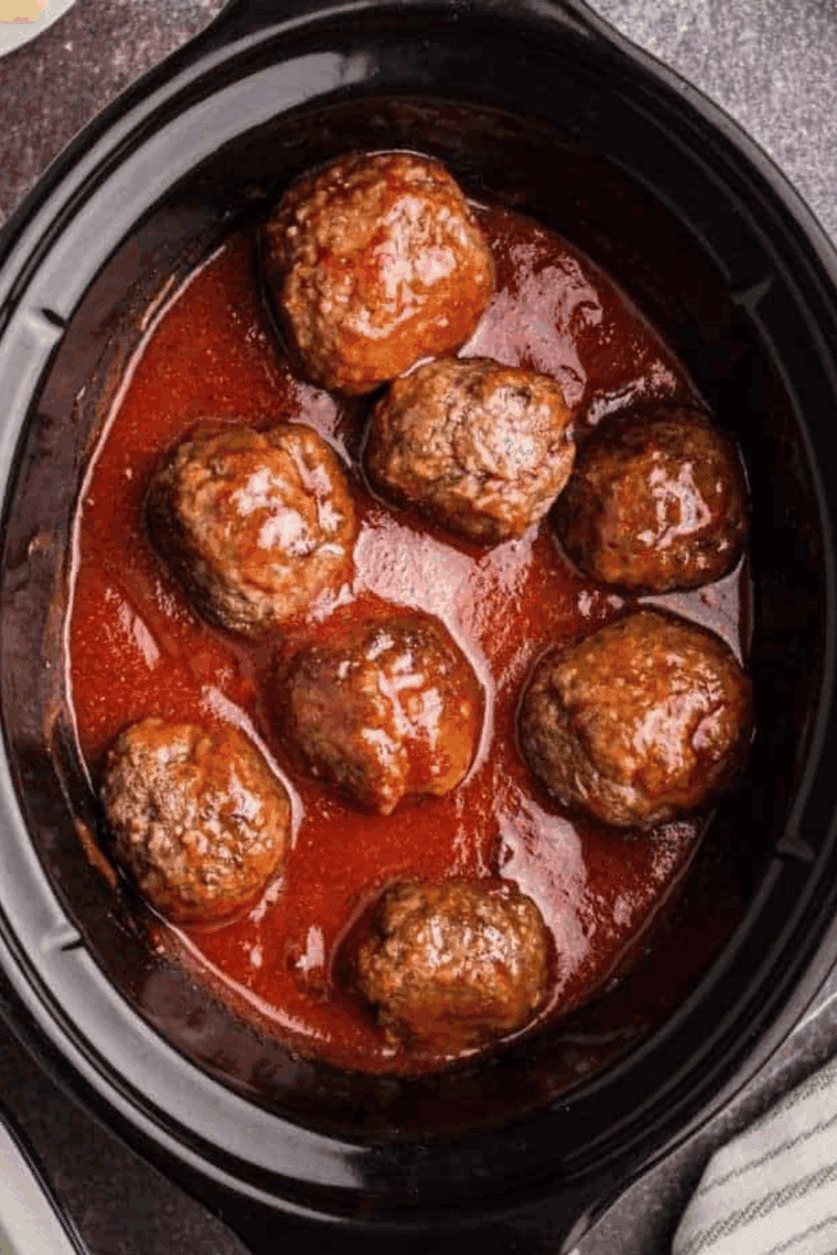 Crock pot filled with cooked frozen meatballs in rich marinara sauce