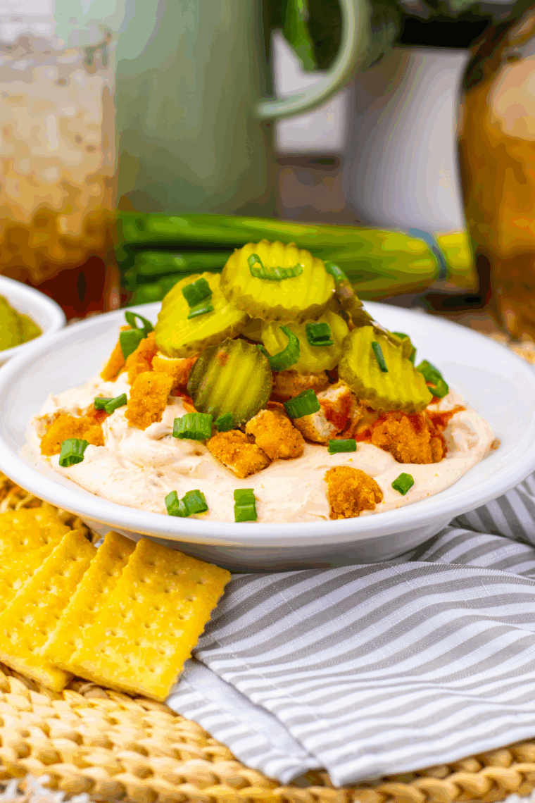 Bowl of Easy Nashville Hot Chicken Dip topped with spicy seasoning and served with chips