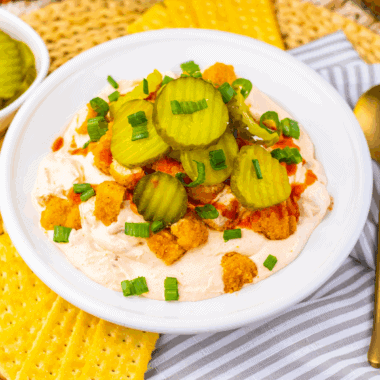 Bowl of Easy Nashville Hot Chicken Dip topped with seasoning and served with chips.