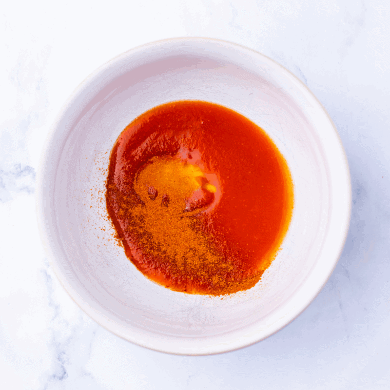 Topping the Nashville Hot Chicken Dip with extra chicken, spicy sauce drizzle, pickles, and scallions.