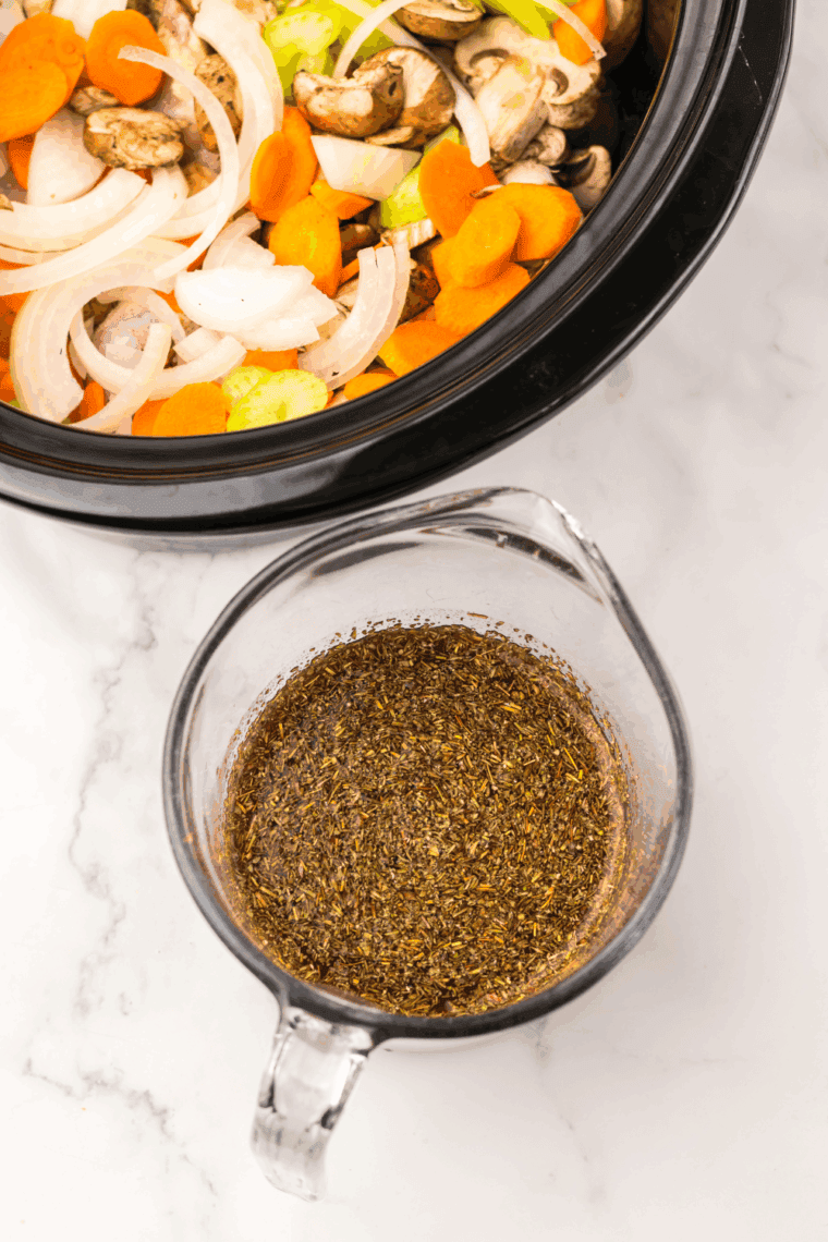 Sliced onions, carrots, celery, mushrooms, and garlic layered over chicken