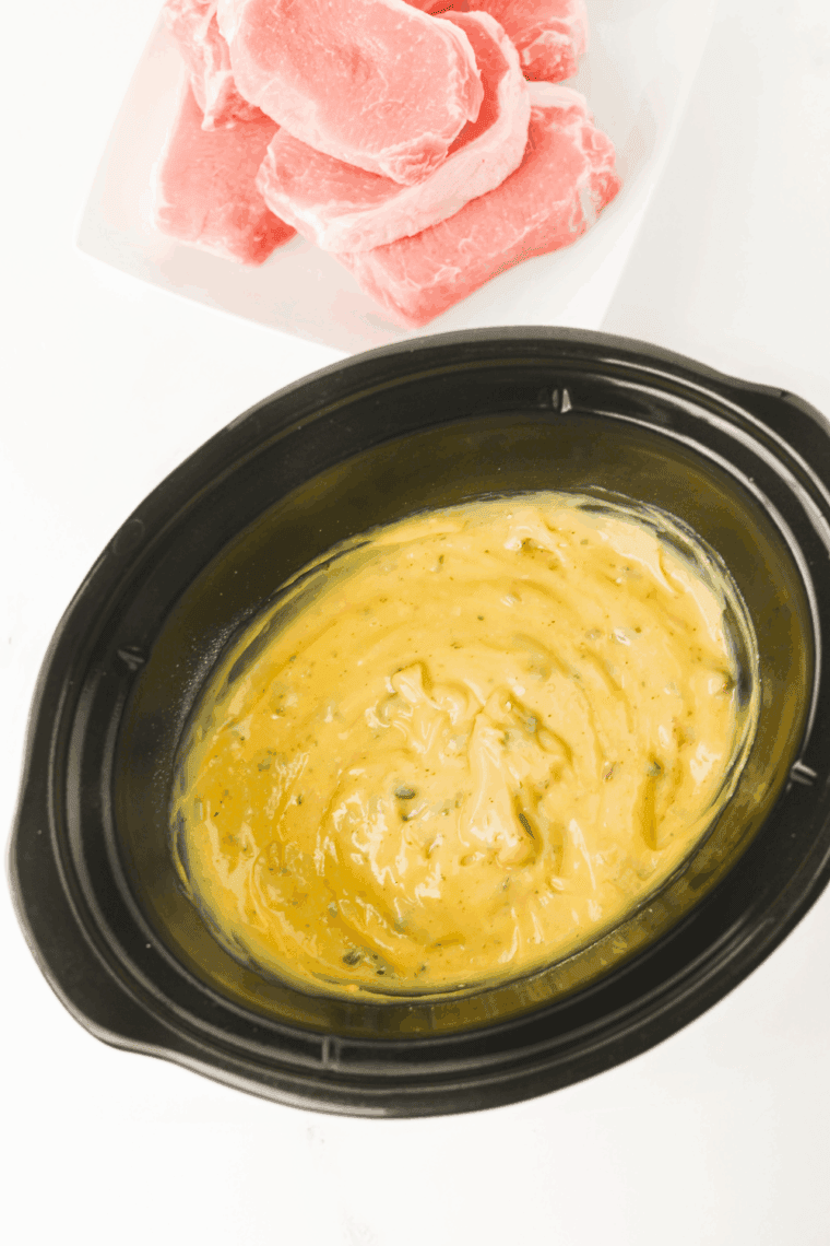 Cream of chicken soup, cream of mushroom soup, and ranch seasoning whisked together in a slow cooker.