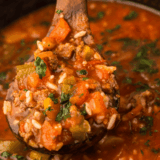 Bowl of easy slow cooker stuffed pepper soup with ground beef, bell peppers, tomatoes, and rice, garnished with herbs.