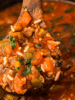 Bowl of easy slow cooker stuffed pepper soup with ground beef, bell peppers, tomatoes, and rice, garnished with herbs.