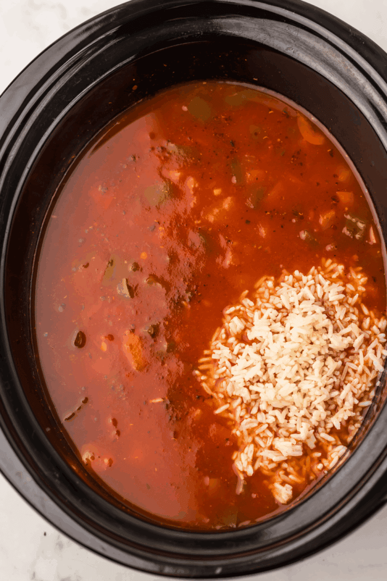 Overhead view of a crockpot filled with colorful Stuffed Pepper Soup featuring green and red bell peppers.