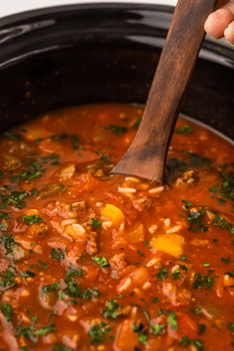 A steaming bowl of Grandma's Slow Cooker Stuffed Pepper Soup garnished with fresh herbs and served with a side of bread.
