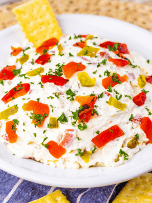 Easy Texas Christmas Dip in a bowl topped with chiles, cheese, and festive garnishes surrounded by tortilla chips.