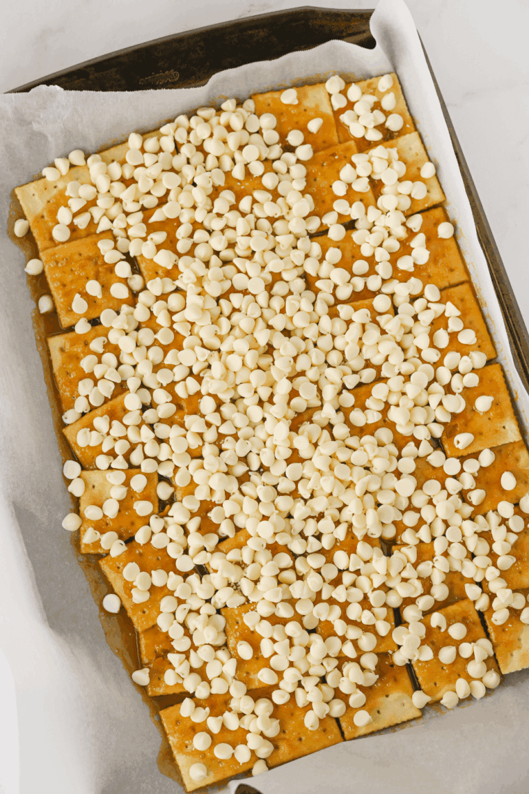 White chocolate chips sprinkled over hot caramel on crackers