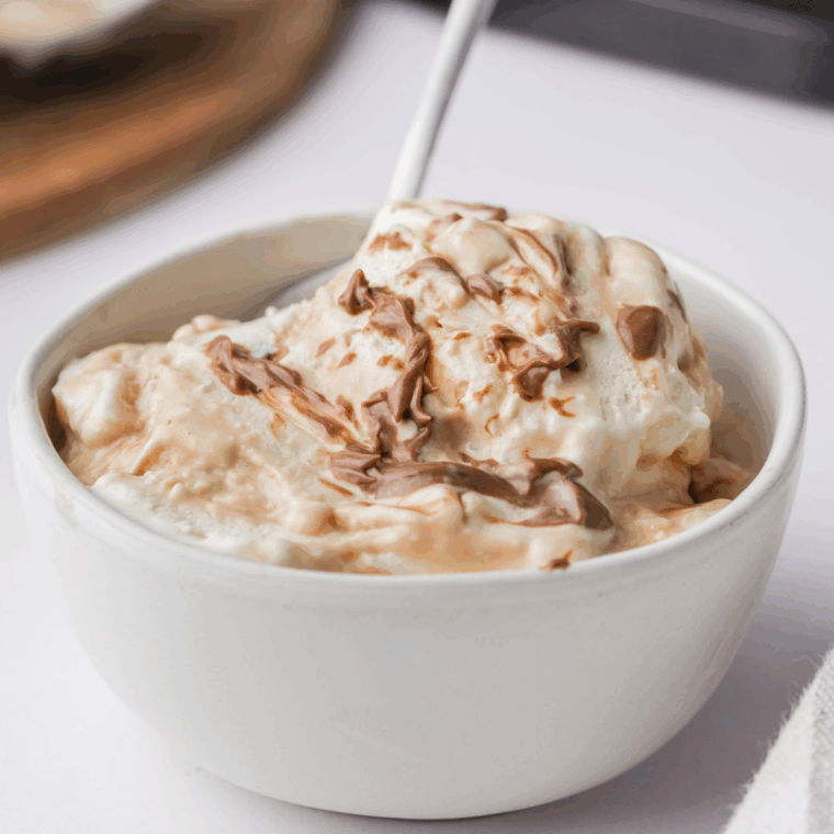 Bowl of Ninja Creami Ben and Jerry’s Vanilla Caramel Fudge ice cream with caramel swirls and chocolate chunks