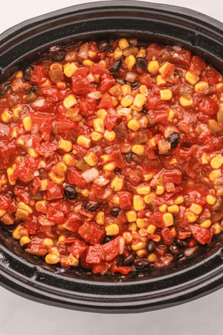 Slow cooker filled with chili ingredients cooking on low heat.