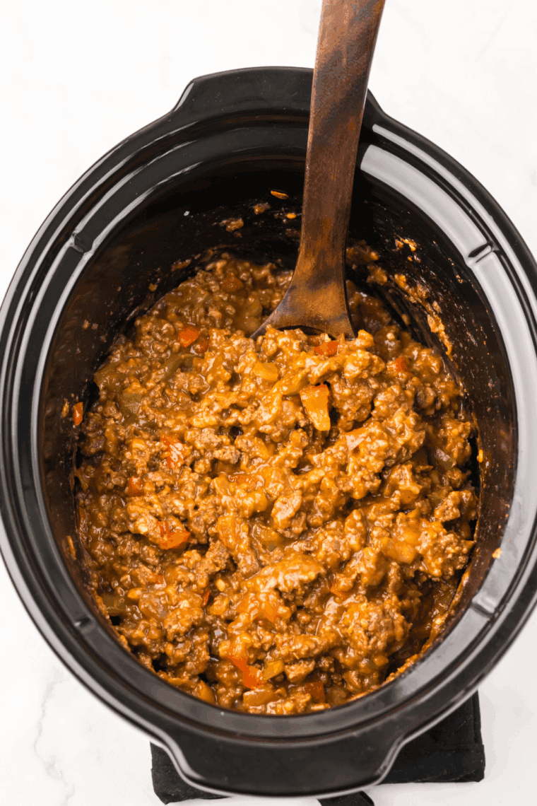 Pouring sauce over beef mixture and stirring gently in slow cooker