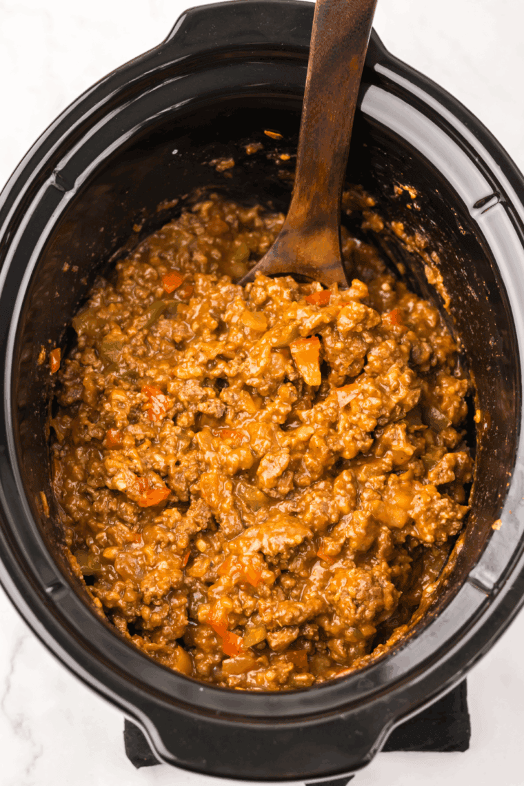 Pouring sauce over beef mixture in slow cooker and stirring gently