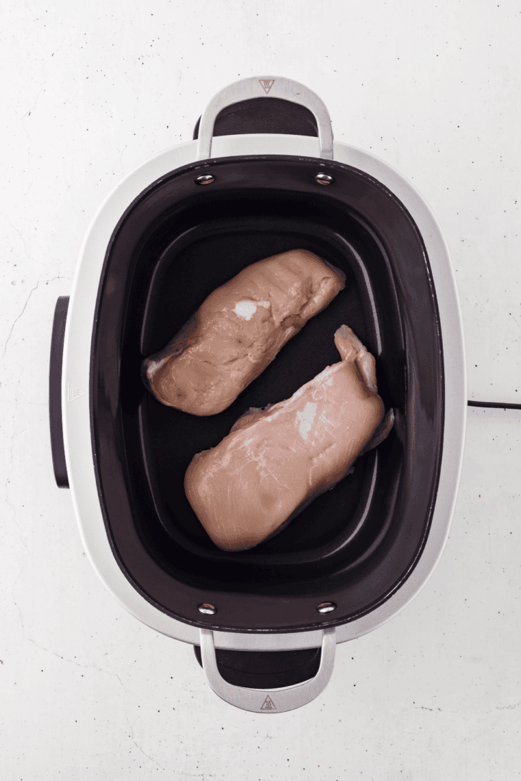 Chicken breasts or thighs placed evenly in the slow cooker.