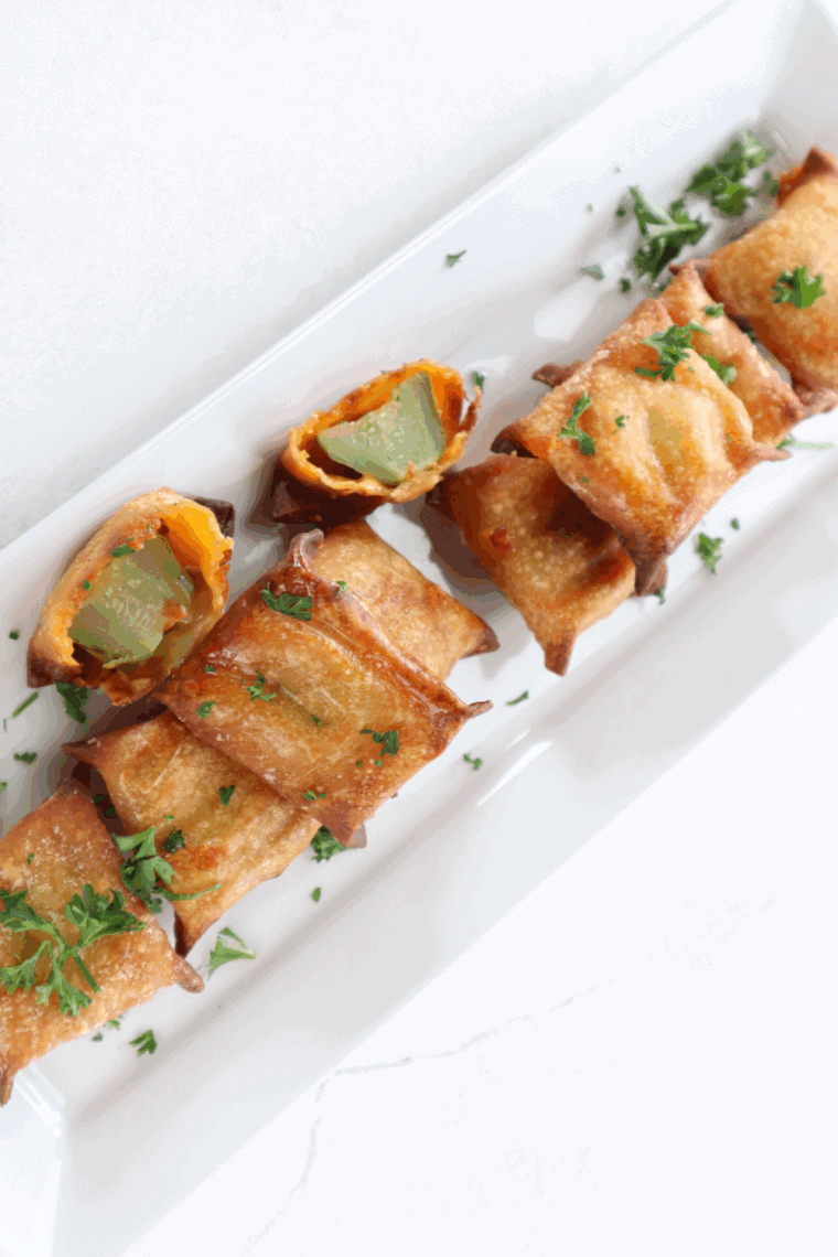 Golden air fryer wontons stuffed with melted cheese and tangy pickles, served on a plate