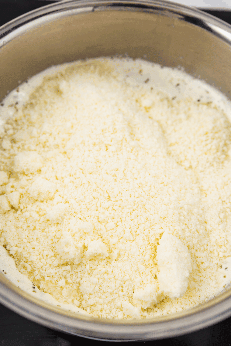 Creamy Alfredo sauce simmering on low heat, thickening gently