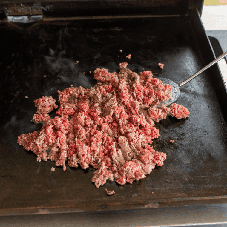 Preheating Blackstone griddle and sautéing onions and garlic until fragrant.