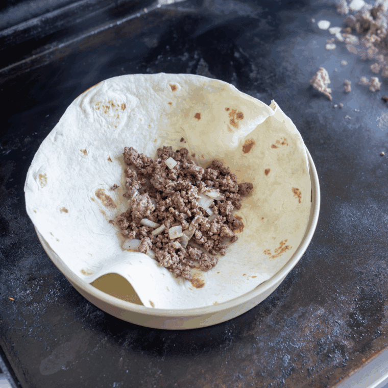 Serving the seasoned Blackstone griddle taco meat with tortillas and toppings like cheese, lettuce, and salsa.