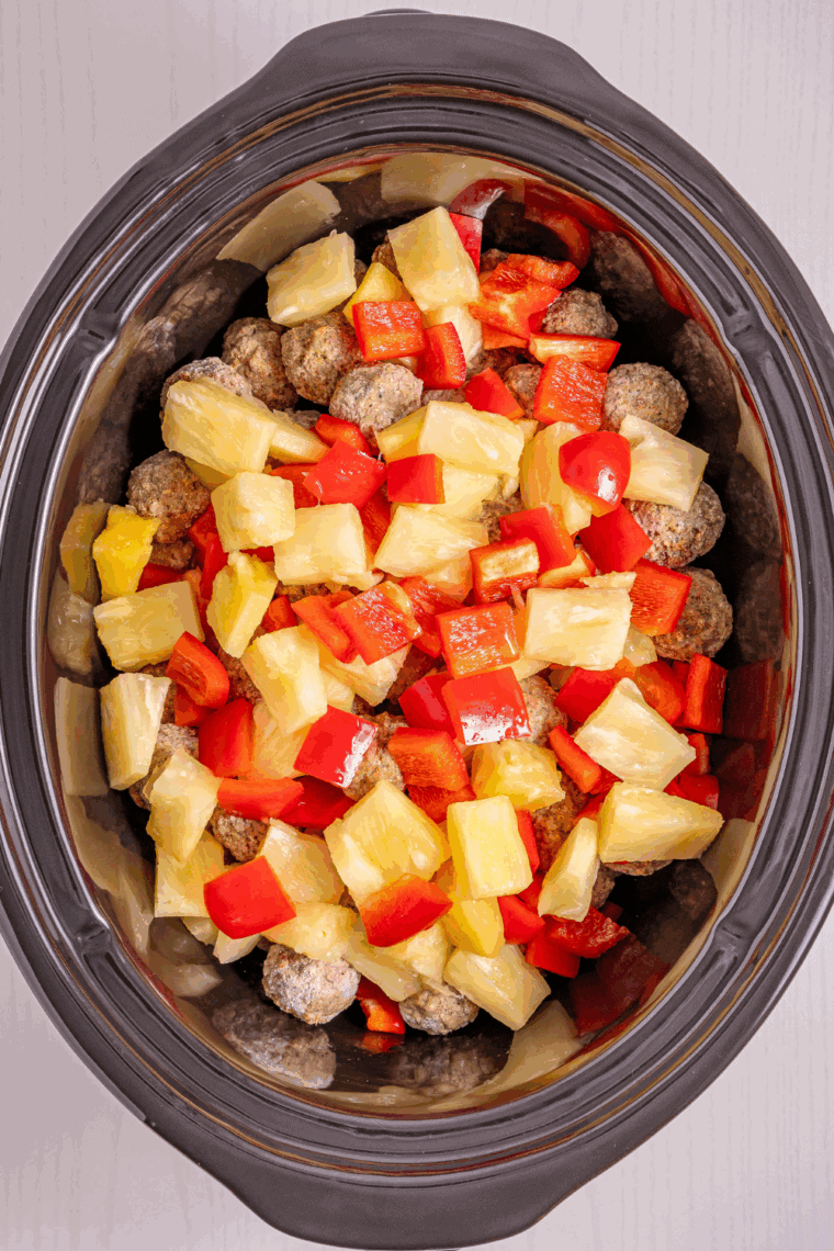 Frozen meatballs, pineapple chunks, and bell peppers added to slow cooker