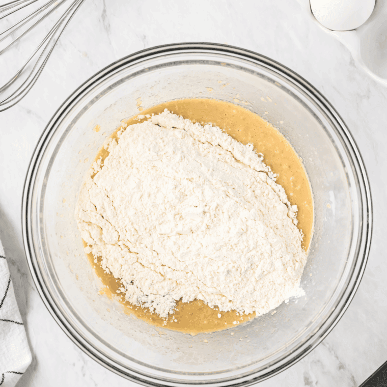 Gradually stirring wet ingredients into dry ingredients to make soft, slightly sticky dough