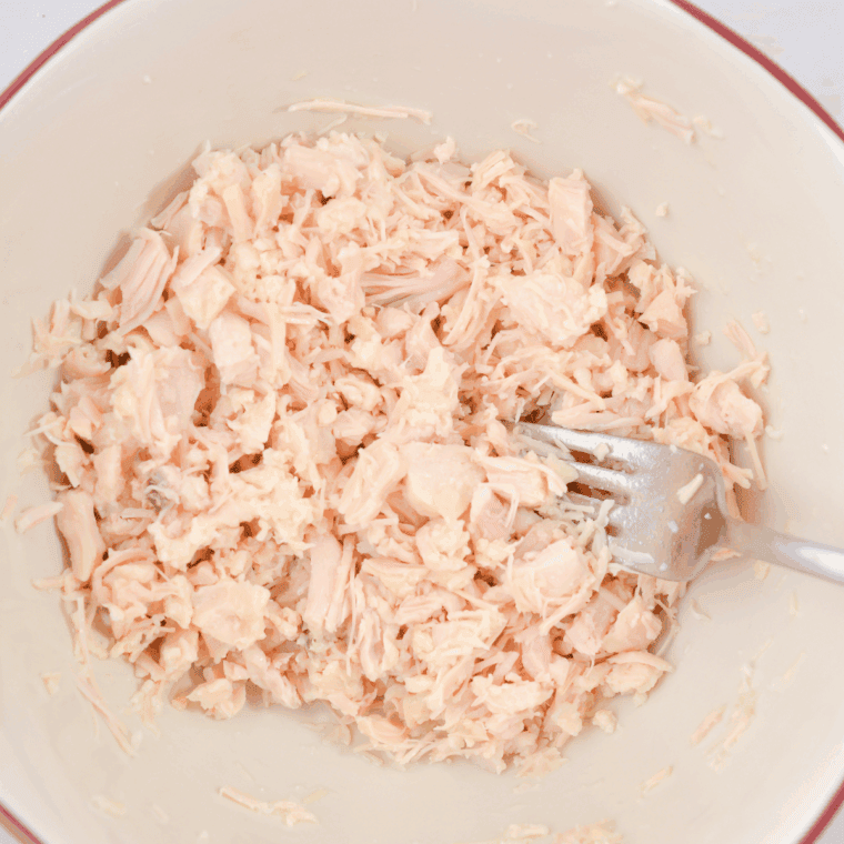 Mixing canned chicken, mayonnaise, pesto, lemon juice, basil, and almonds in a bowl