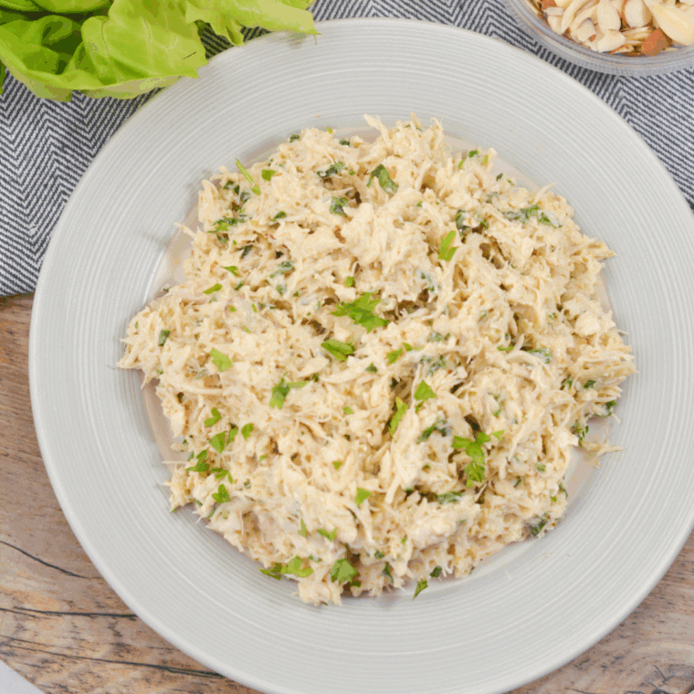 Creamy chicken salad without celery in a bowl, garnished with fresh basil and sliced almonds, ready to serve.