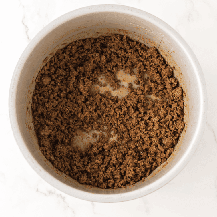 Browning ground beef and breakfast sausage in a large skillet, breaking the meat into small crumbles for dirty rice.