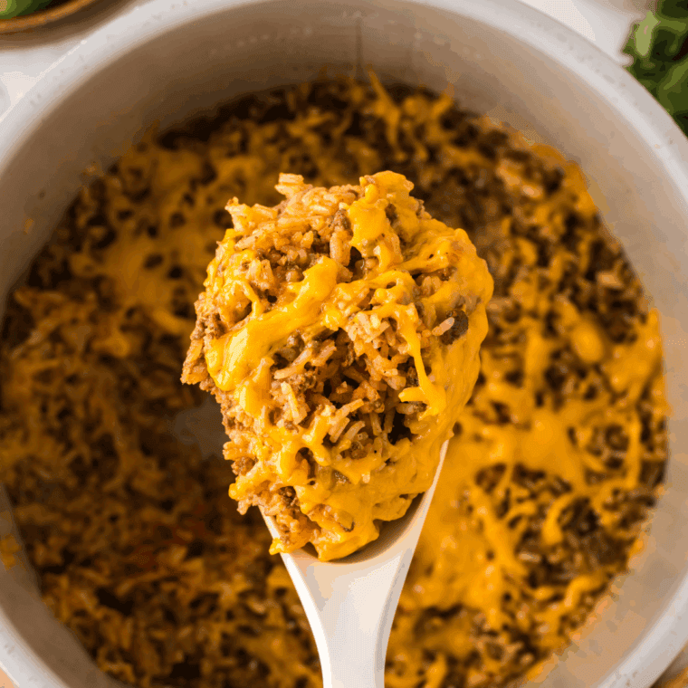 Stirring uncooked rice, beef broth, and Cajun spices into the meat and vegetable mixture in a Dutch oven.