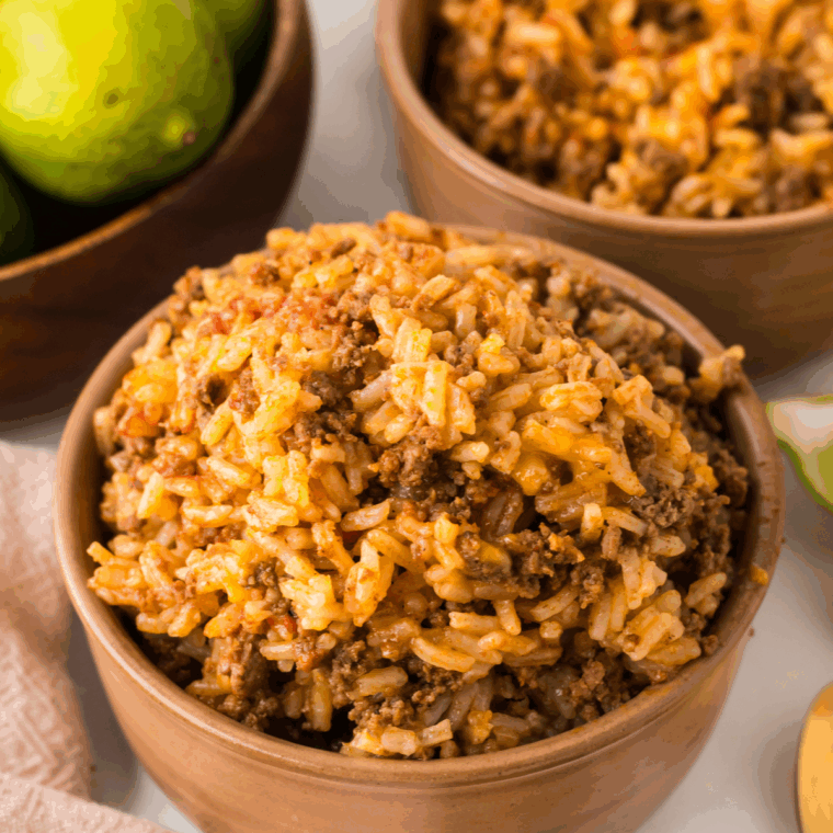 A spoonful of fluffy dirty rice being lifted from a bowl, steam rising.
