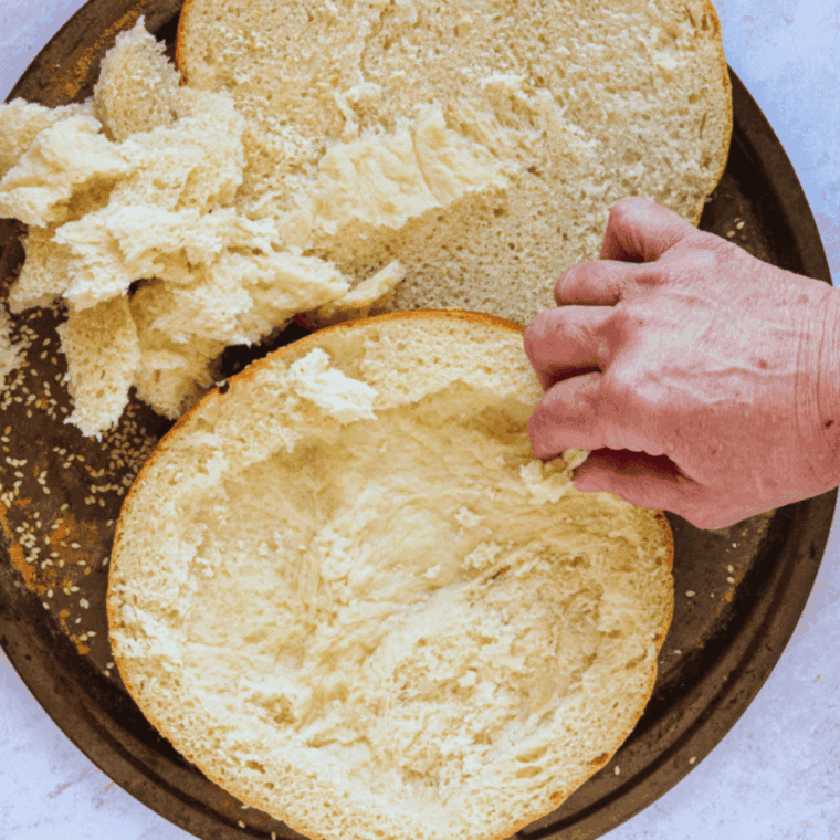 A large round Italian bread loaf sliced horizontally with a thick layer of olive salad spread on both sides.